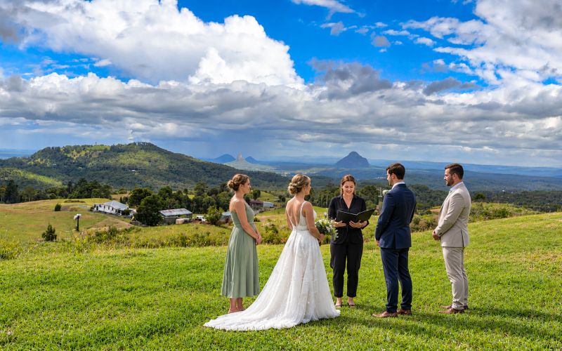 A small ceremony on the grass at On The View, the Glasshouse Mountains in the distance